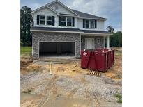 New two-story home boasts stone accents, a covered porch, and an attached two-car garage with open access at 193 Falls Of The Cape Dr, Lillington, NC 27546