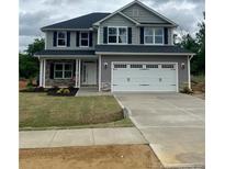 Charming two-story home with a well-manicured lawn and a two-car garage at 203 Lake Edge Dr, Lillington, NC 27546