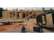View of a construction site with partially framed house and trailer with a worker on the frame at 214 Uwharrie Way, Sanford, NC 27330