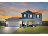 Inviting two-story home featuring a well-manicured lawn and attached two-car garage at sunset at 58 Harvest Ct, Linden, NC 28356