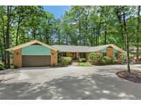 Charming single-story brick home featuring a sprawling front yard and attached two-car garage nestled among mature trees at 3113 Chipping Wedge, Sanford, NC 27330