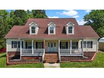 Inviting home featuring a charming front porch, well-maintained lawn, and traditional architectural details at 4085 Alston Bridge Rd, Siler City, NC 27344
