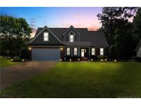 Charming two-story home featuring manicured lawn, brick accents, attached garage, and traditional architectural details at 626 Orchard Falls Dr, Spring Lake, NC 28390