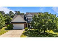 Charming two-story home featuring a brick facade, attached garage, and a well-maintained front lawn with mature trees at 81 Checkmate Ct, Cameron, NC 28326