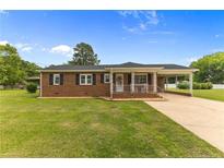 Charming single-story brick home with a welcoming front porch and well-manicured lawn at 209 4Th St, Erwin, NC 28339