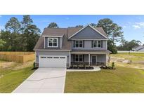 Charming two-story home with a two-car garage, gray siding, manicured lawn, and a welcoming entrance at 225 Persimmon Tree Dr, Cameron, NC 28326