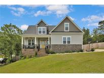 Charming two-story home with a well-manicured lawn, stone accents, and a inviting front porch at 576 Executive Dr, Lillington, NC 27546