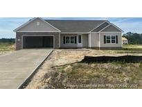 Charming one-story home featuring stone accents, an attached garage, and a well-manicured lawn at 107 Camp Rock Rd, Lillington, NC 27546