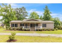 Charming single-story home with a welcoming front porch and manicured landscaping at 2003 Spring Ln, Sanford, NC 27330