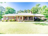 Charming brick home featuring a metal roof, a front porch and a spacious front yard at 3897 Olivia Rd, Sanford, NC 27332