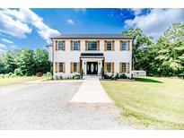 Charming two-story home with white siding, wood shutters, black roof, and beautiful landscaping at 1001 Dycus Rd, Sanford, NC 27330