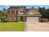 Charming two-story home features a brick facade, attached two-car garage, and lush green lawn at 106 Linden Rd, Cameron, NC 28326