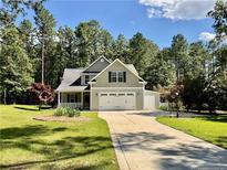 Charming two-story home with a well-manicured lawn, mature trees, and a spacious driveway leading to a two-car garage at 147 Sherwood Ln, Sanford, NC 27332