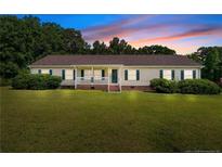 Charming ranch style home features a covered front porch, green lawn, and mature trees at 2901 Cheshire Dr, Sanford, NC 27332