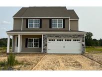 Two-story home with stone accents, two-car garage and newly poured driveway on a construction lot at 136 Camp Rock Rd, Lillington, NC 27546