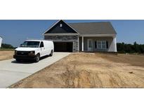 View of the home's exterior with a stone-accented garage and a light gray siding under a gray shingled roof at 155 Camp Rock Rd, Lillington, NC 27546