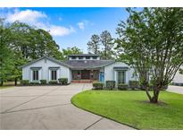 Charming home with a manicured lawn, circular driveway, and rocking chairs on the front porch at 38 East Lndg, Sanford, NC 27332