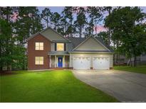 Charming two-story brick and siding home featuring a well-maintained lawn, two-car garage, and blue front door at 46 Wateredge Ln, Sanford, NC 27332