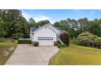 Charming single-Gathering home featuring a two-car garage, brick accents, and mature landscaping in a quiet neighborhood at 6301 Mockingbird Ln, Sanford, NC 27332