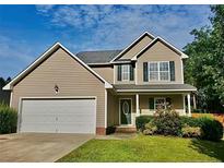 Charming two-story home with a well-manicured lawn, attached garage, and inviting front porch at 1824 Ponderosa Trl, Cameron, NC 28326