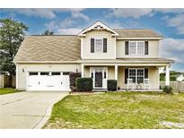 Charming two-story home with a well-manicured lawn, attached garage, and welcoming front porch at 12 Schoomaker Ct, Broadway, NC 27505