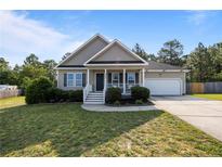 Charming single-Gathering home featuring a well-maintained lawn, manicured bushes, and a covered front porch at 187 Gunner Ct, Broadway, NC 27505