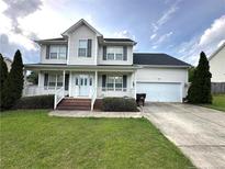 Charming two-story home with a welcoming front porch, landscaped yard, and attached two-car garage at 554 Lenoir Dr, Spring Lake, NC 28390
