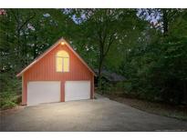 Detached two-car garage with white doors and an arched window surrounded by lush trees at 1116 Falling Strm, Sanford, NC 27332