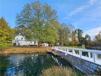 Scenic view of a charming white house with a dock and bridge overlooking a tranquil pond with a fountain at 3647 Olivia Rd, Sanford, NC 27332
