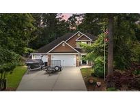 Charming two-story home with manicured lawn, two-car garage, and boat parked in the driveway at 69 Night Heron Ct, Sanford, NC 27332