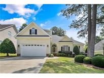 Charming yellow home featuring a well-manicured lawn, an attached garage, and mature trees at 196 Leaning Pine Cir, Spring Lake, NC 28390