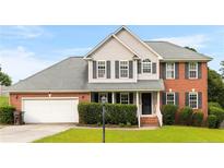 Charming two-story home with brick and siding, a well-manicured lawn, and an attached two-car garage at 225 Woodshire Dr, Lillington, NC 27546