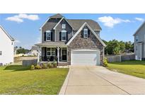 Charming two-story home with a manicured lawn, stone accents, and a two-car garage at 334 Bunting Dr, Lillington, NC 27546