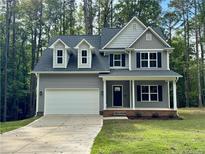Charming home featuring a two-car garage, a covered porch, and meticulous landscaping at 7057 Oak Rd, Sanford, NC 27332