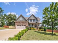 Beautiful two-story home with a stone facade, lush landscaping, and a two-car garage at 416 Kentucky Derby Ln, Lillington, NC 27546