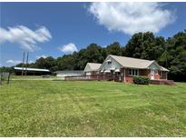Quaint brick home with a metal roof, wooden deck, and a sprawling lawn at 472 Walter Bright Rd, Sanford, NC 27330