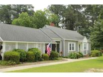 Charming single-story home with gray siding, white trim, landscaped yard, and a welcoming front porch adorned with an American flag at 4903 Lemon Springs Rd, Sanford, NC 27332