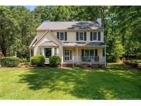 Charming two-story home with a well-manicured lawn, mature trees, and inviting front porch at 609 Fairway Dr, Sanford, NC 27330