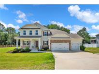 Charming two-story home with a manicured lawn, three-car garage, stone accents, and inviting front porch at 66 S Hawks Ridge Ln, Smithfield, NC 27577