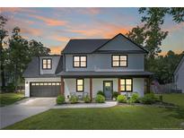 Charming two-story home with manicured lawn, covered porch, and an attached garage, radiating curb appeal at sunset at 182 Navaho Trl, Sanford, NC 27332