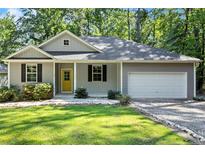 Charming single-story home with gray siding, black shutters, a welcoming yellow front door, and an attached two-car garage at 1541 Louisiana, Sanford, NC 27332