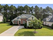 Charming, light yellow house featuring a brick entryway, dormers, manicured lawn and mature landscaping at 259 Rolling Pines Dr, Spring Lake, NC 28390