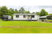 Charming single-story home with a well-maintained lawn, complemented by a covered carport and chain link fence at 411 Rainey Dr, Spring Lake, NC 28390