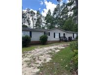 Ranch-style home with gray siding, dark shutters, and an unpaved driveway surrounded by lush trees at 47 Hunter Field, Sanford, NC 27332