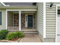 Inviting entryway with a dark-colored front door, stone accents, and covered porch at 19 Fifty Caliber Dr, Broadway, NC 27505