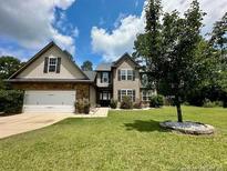 Charming home featuring a well-manicured lawn, mature trees, and a classic two-car attached garage at 110 Citadel St, Cameron, NC 27326