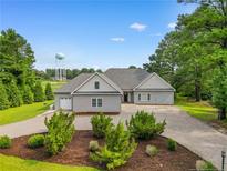 Charming single-story home with gray siding, mature landscaping, and long driveway at 56 Indian Trl, Sanford, NC 27332