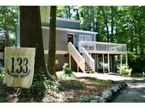 Charming home with a welcoming front porch, nestled among mature trees and lush landscaping, with house number sign at 133 Bonnell Ct, Cary, NC 27511