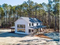 Stunning two-story modern farmhouse with board and batten siding surrounded by a lush forest at 1418 Crawford Dairy Rd, Pittsboro, NC 27312