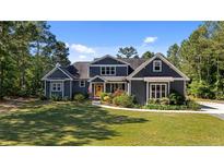 Charming two-story home featuring a yellow door, manicured lawn, and mature landscaping at 1063 Pineywood Church Rd, Cameron, NC 28326